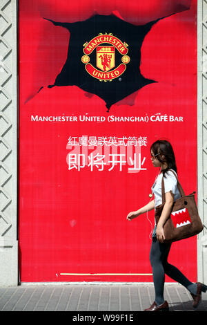 ---- Eine junge chinesische Frau geht hinter einem-bald-Öffnen der Manchester United Cafe Bar in Shanghai, China, 18. Mai 2011. Der amerikanische Besitzer von der Manche Stockfoto