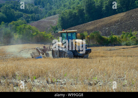 Toskana, Italien, 23. SEPTEMBER 2017: Gelb Caterpillar Tractor mit einem auf einem Gemähten Feld auf einen Tag im September Pflug Stockfoto