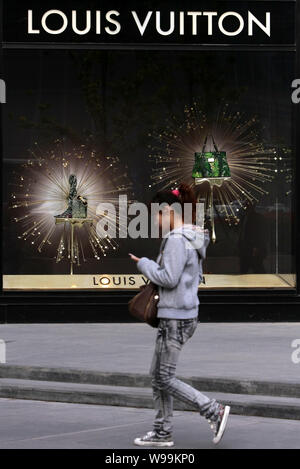 ---- Eine junge chinesische Frau geht Vergangenheit ein Louis Vuitton (LV) Boutique in Nanjing City, East China Jiangsu Provinz, 22. April 2011. Nach Th Stockfoto