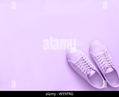 Violette Ledersneaker auf violettem Hintergrund. Paar violette Sportschuhe oder Sneaker mit Platz für Text oder Design. Overhead-Aufnahme der neuen violetten Sneaker, monochrom. Draufsicht oder flache Lage Stockfoto