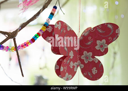 paper butterflies, beads and other things hanging from the window of the preschool in Roback Stockfoto