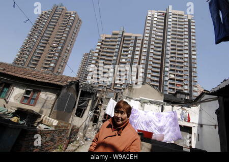 --FILE - eine chinesische Frau Spaziergänge inmitten von alten Häusern vor neue moderne Wohn- Apartment Gebäude in Shanghai, China, 11. März 201 abgerissen. Stockfoto
