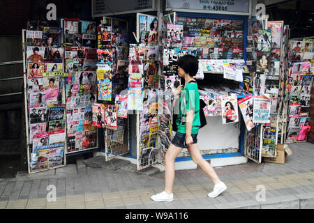 ---- Eine junge chinesische Frau geht vorbei an einem Zeitungskiosk in Peking, China, 7. August 2010. China hat Zeitungen, Verlage verboten und die Web site Inhaber, fr Stockfoto