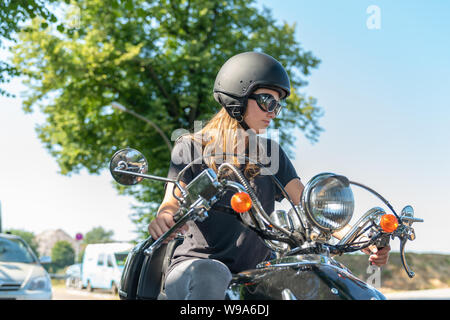 Junge Frau fährt einen Scooter und sieht im Rückspiegel Stockfoto