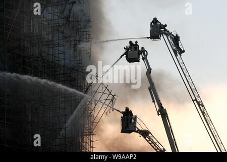 Chinesische Feuerwehrmänner Schlauch Wasser das Feuer in einem Mehrfamilienhaus in der Innenstadt von Shanghai, China, 15. November 2010 zu löschen. Eine Apartme Stockfoto