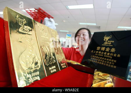 Ein chinesischer Mitarbeiter zeigt drei Shanghai Expo-themed Gold Bars in einer Welt Expo Franchise Store in Shanghai, China, 12. Mai 2010. Die drei reines Gold b Stockfoto