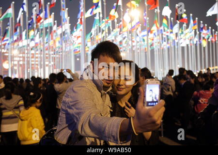 Ein Chinesisches paar Fotos vor der nationalen Flaggen der Länder der Welt Expo 2010 Teilnehmenden während der Eröffnungsfeier der Welt Stockfoto