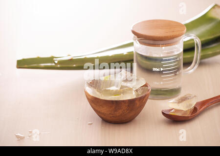 Schüssel mit geschälten Aloe vera und grüne Blätter auf hölzernen Hintergrund Stockfoto