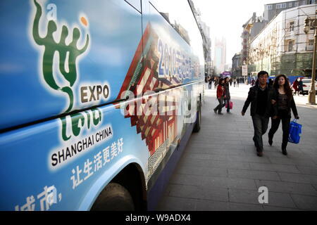 Lokale chinesische Bewohner Spaziergang, vorbei an einem Bus mit Werbung für die World Expo 2010 Shanghai, Tianjin, China, 1. April 2010. Mit der schnellen approachi Stockfoto