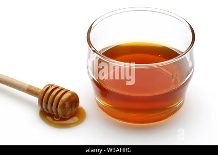 Honig tropft vom Pendelarm und Honig im Glas Schüssel auf weißem Hintergrund Stockfoto