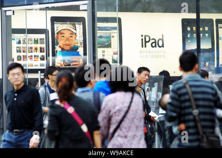 ------ Lokale chinesische Bewohner Spaziergang, vorbei an einem Apple Store, in dem die Kunden einkaufen vor eine Werbung für das Apple iPad in Peking sind, C Stockfoto