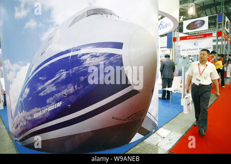 ---- Ein chinesischer Besucher Wanderungen vorbei an einem Werbeplakat für die Boeing 747-400ERF am Stand der AirBridge Cargo während einer Messe in Shanghai, China Stockfoto