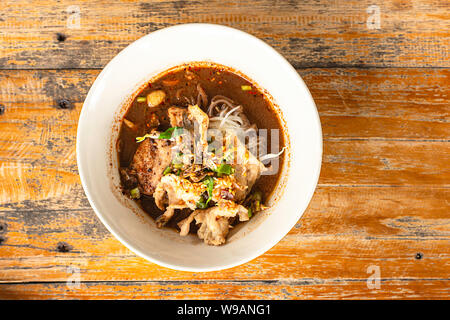 Pikant Schwein Nudeln fällt in eine weiße Tasse auf einem Holztisch. Stockfoto