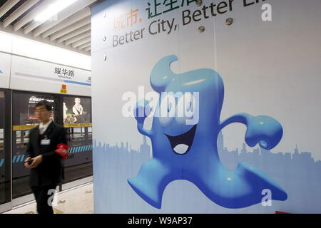 Eine Chinesische metro Arbeiter Wanderungen vorbei an einem Werbeplakat für die Weltausstellung Expo 2010 mit dem Bild des Haibao, dem offiziellen Maskottchen der Shanghai Expo, an Stockfoto
