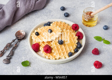 Wellpappe Waffel Kekse mit frischen Himbeeren und Blaubeeren auf einen konkreten Hintergrund. Platz kopieren Stockfoto