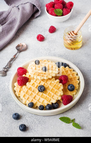 Wellpappe Waffel Kekse mit frischen Himbeeren und Blaubeeren auf einen konkreten Hintergrund. Platz kopieren Stockfoto