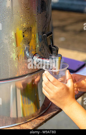 Hand junge Holding das Glas mit Wasser aus dem Kühler. Stockfoto