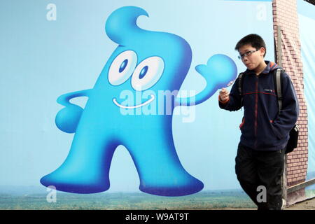 Ein chinesischer Student Wanderungen vorbei an einem Werbeplakat für die Weltausstellung Expo 2010 mit dem Bild des Haibao, dem offiziellen Maskottchen der Shanghai Expo, in Shan Stockfoto