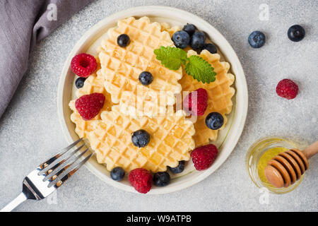 Wellpappe Waffel Kekse mit frischen Himbeeren und Blaubeeren auf einen konkreten Hintergrund. Platz kopieren Stockfoto