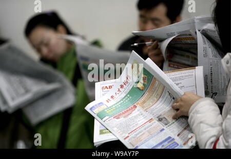 Chinesische Arbeitsuchende lesen Zeitungen mit Stellenanzeigen, der bei einem Job Messe in Peking, China, 25. Februar 2010. Mehr als 6.3 Universität und Hochschule stud Stockfoto