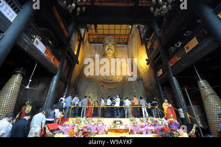 Chinesische Besucher ansehen Arbeitnehmer regilding Eine alte Buddha Statue in der Großen Buddha Tempel Tongnan in Chongqing, China, 26. Mai 2010. In Tang gebaut Stockfoto