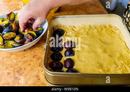 Oma backen Pflaumenkuchen. Hausgemachtes Gebäck. Fruit Cake. Hand von einer alten Frau in der Küche arbeitet Stockfoto