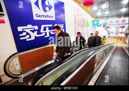 ------ Chinesische Volk der Rolltreppe in einem Supermarkt Carrefour in Changsha City, Central China Provinz Hunan, 4. März 2010. Französische Einzelhandel gi Stockfoto