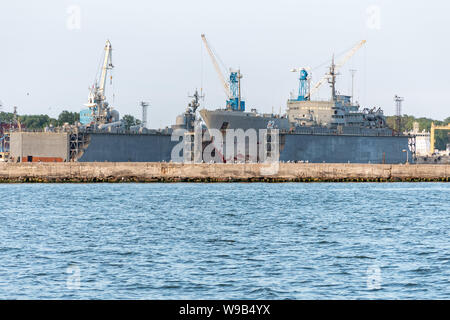 Großen eisernen Navy Schiffe in der Werft zur Reparatur. Großer Kran in der Werft. Blaue Meer Hafen Stockfoto