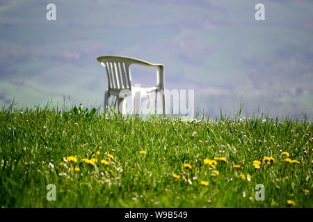 Ein Stuhl aus Kunststoff auf einer Wiese in den Bergen, ein Moment der einfachen Entspannen in der Natur Stockfoto