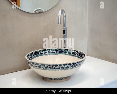 Sauber Loft style Bad Interieur mit Porzellan Waschbecken Waschbecken Wasserhahn auf weißem Marmor Regal und runden Spiegel auf Beton Wand Hintergrund. Stockfoto