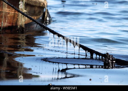 Ein Seil von einem Versand Boot auf dem Meer von Rohöl, die nach einer Pipeline Explosion in Dalian verschüttete abgedeckt ist, im Nordosten China Liaoning prov Stockfoto