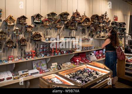 Eine Frau an Kuckucksuhren in einem Schweizer Souvenir Shop suchen Stockfoto