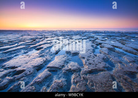 Der Strand bei Ebbe durch das Watt und ein farbenfroher Sonnenuntergang im Sommer - Bild - Wattenmeer, Niederlande Stockfoto