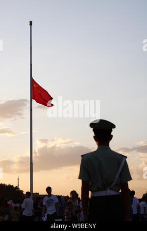 Einem chinesischen paramilitärischen Polizist wacht neben der chinesischen nationalen Flagge auf Halbmast Opfer des Zhouqu Schlammlawinen auf dem Platz des Himmlischen Friedens zu trauern. Stockfoto