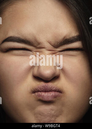 Nahaufnahme, Porträt der jungen und emotionale chinesische Frau. Sehr detail photoshot der weiblichen Modell mit gepflegter Haut und helle Gesichtsausdruck. Konzept der menschlichen Emotionen. Ekel. Stockfoto