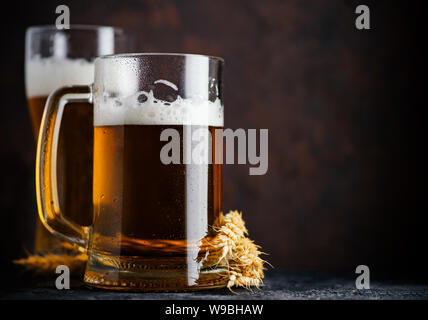 Ein Glas Bier und ein Bier Glas auf einem dunklen Hintergrund. Weizen deutsches Bier. Oktoberfest. dunkelbraun Copyspace Hintergrund Stockfoto