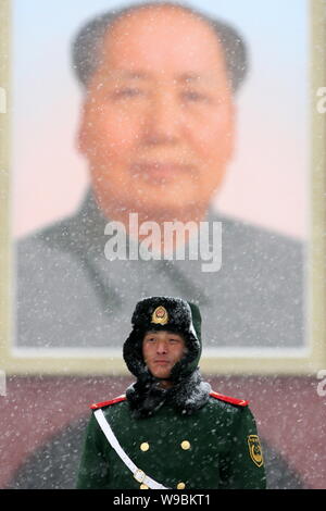Einem chinesischen paramilitärischen Polizist wacht in einem schweren Schnee vor dem Portrait des ehemaligen chinesischen Führer Mao Zedong auf dem Platz des Himmlischen Friedens Stockfoto