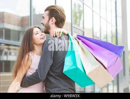 Junge Geliebte umarmen mit Tüten auf der Straße Stockfoto