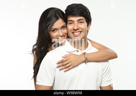 Junge Frau, einen Mann von hinten umarmt und lächelnd Stockfoto