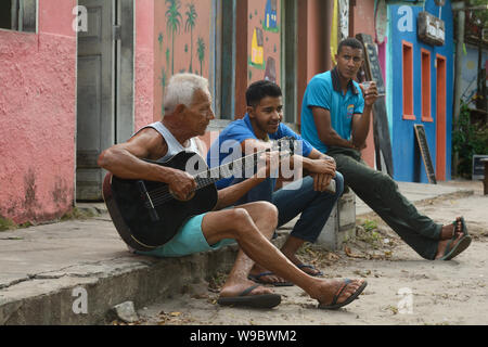 Drei Männer auf dem Bürgersteig in Caraiva, Bahia, Brasilien sitzen. Stockfoto