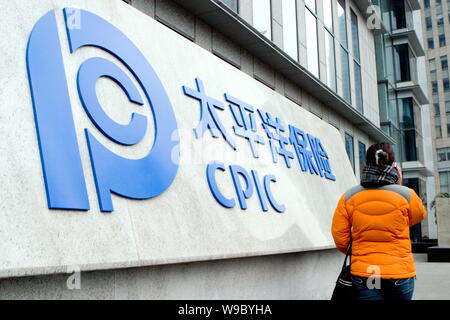 ---- Eine junge chinesische Frau geht vorbei an einer Tafel von CPIC (China Pacific Insurance (Group) Co., Ltd.) in Shanghai, China, 11. Februar 2008. China Stockfoto