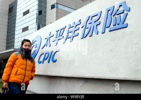 ---- Eine junge chinesische Frau geht vorbei an einer Tafel von CPIC (China Pacific Insurance (Group) Co., Ltd.) in Shanghai, China, 11. Februar 2008. China Stockfoto