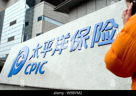 ---- Eine junge chinesische Frau geht vorbei an einer Tafel von CPIC (China Pacific Insurance (Group) Co., Ltd.) in Shanghai, China, 11. Februar 2008. China Stockfoto