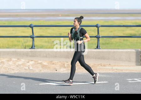 Southport, Merseyside. UK Wetter. 13 Aug, 2019. Schönen sonnigen Start in den Tag als Anwohner am frühen Morgen übung auf der Strandpromenade. Credit: MediaWorldImages/Alamy leben Nachrichten Stockfoto