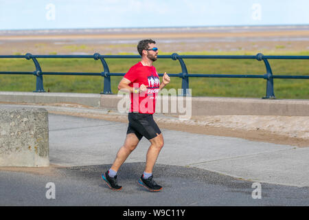 Southport, Merseyside. UK Wetter. 13 Aug, 2019. Schönen sonnigen Start in den Tag als Anwohner am frühen Morgen übung auf der Strandpromenade. Credit: MediaWorldImages/Alamy leben Nachrichten Stockfoto