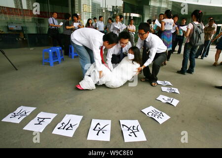 Chinesische Arbeiter versuchen, ein Kollege Studentin, die ihren Körper mit Gaze eingewickelt Unterstützung für Deng Yujiao, ein Hotel, Kellnerin, die eine Erstochen zu zeigen zu tragen Stockfoto