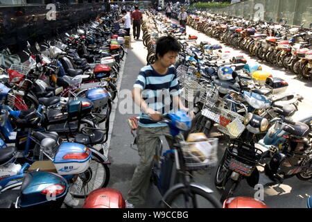 ---- Ein chinesischer Radfahrer fährt mit dem Fahrrad unter Reihen von Fahrräder und E-Bikes auf einem Parkplatz in Peking, China, 4. September 2008. Stockfoto