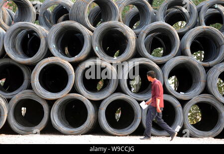 ---- Ein chinesischer Arbeiter Spaziergänge Vergangenheit Rollen aufgewickelt Stahldrähte in einem Stahl Produkte Markt in Peking, China, 4. Mai 2009. China Rohstahlproduktion Stockfoto