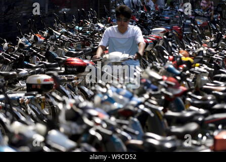 ---- Ein chinesischer Radfahrer fährt mit dem Fahrrad unter Reihen von Fahrräder und E-Bikes auf einem Parkplatz in Peking, China, 4. September 2008. Stockfoto