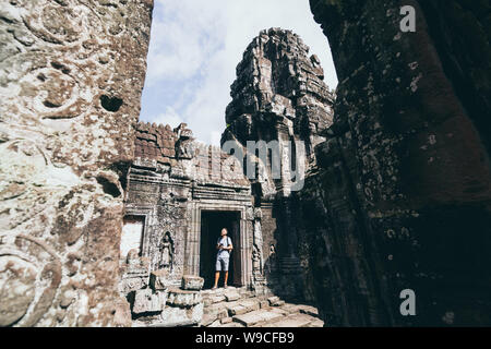 Kaukasische Mann mit Kamera ansehen unter den Ruinen der Tempelanlage Angkor Wat, Siem Reap, Kambodscha. Stockfoto